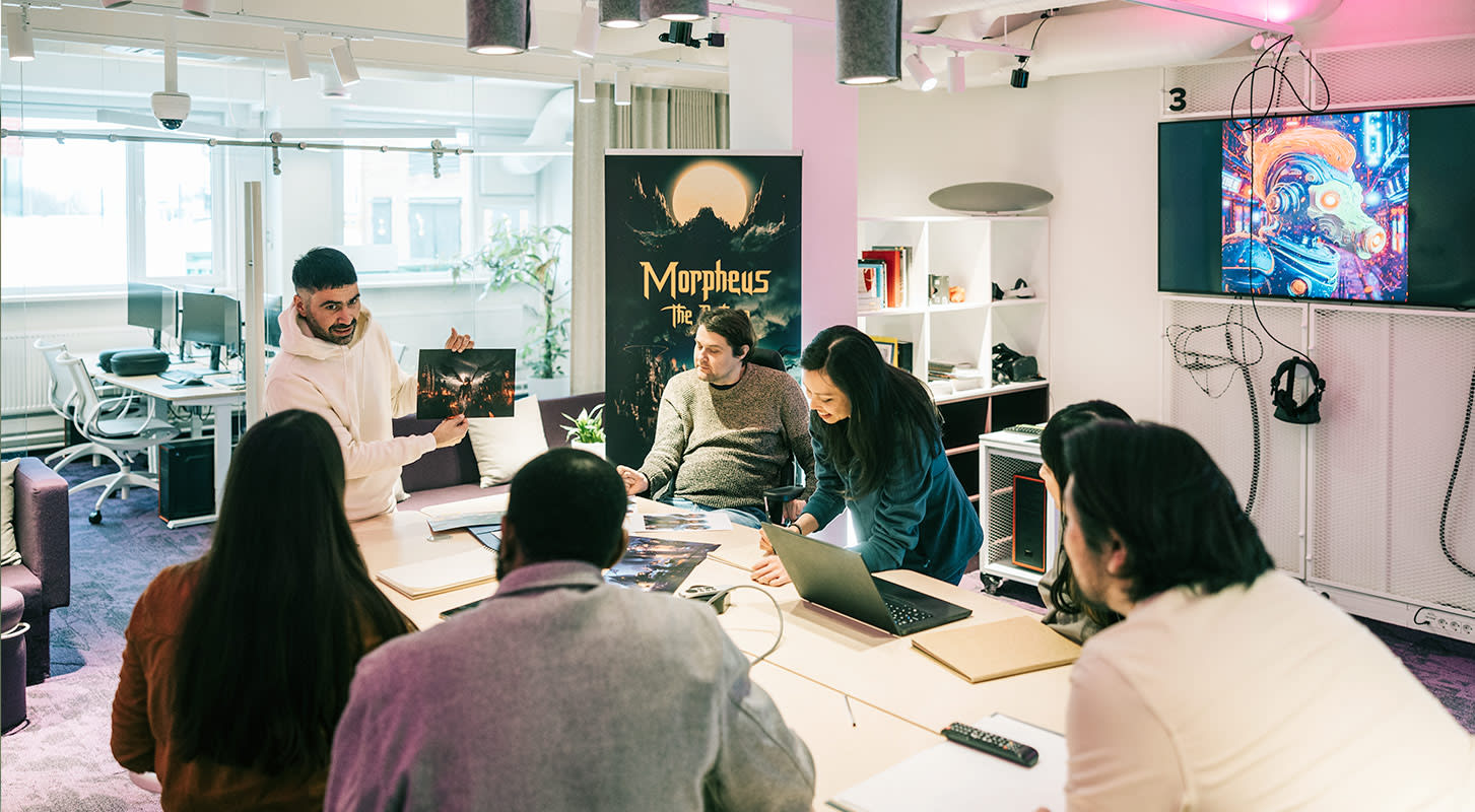 A diverse group of people collaborating around a table, each using laptops for a productive discussion.